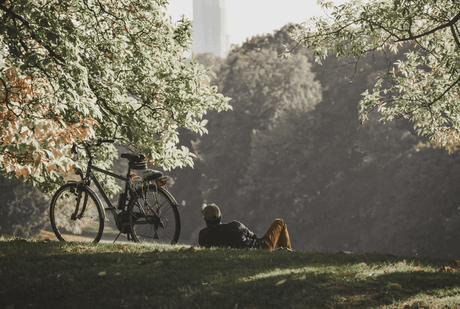 a man sits near his e-bike on the grass