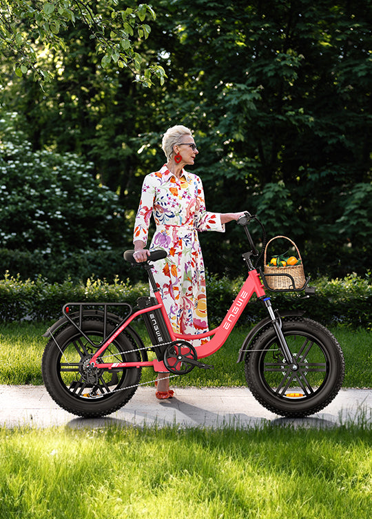 Eine Frau steht neben dem flamingorosa rosa E-Bike Engwe L20