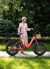 Eine Frau steht neben dem flamingorosa rosa E-Bike Engwe L20
